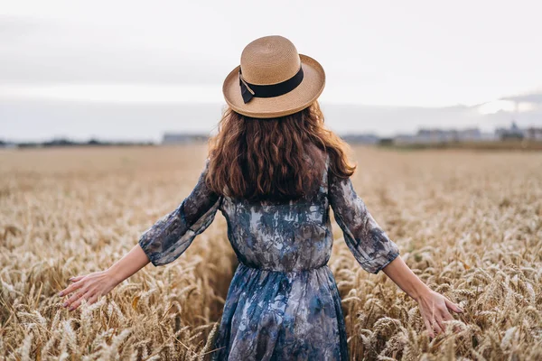 一个头发卷曲的年轻漂亮女子的画像 穿着衣服头戴帽子的女人站在麦田里 背景色 — 图库照片