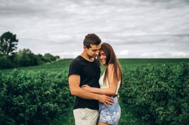 Genç aşıklar yeşil frenk üzümü tarlalarının arka planında nazikçe sarılıyorlar. Aşk Hikayesi.