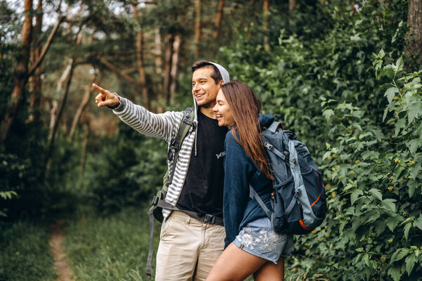 Young couple with backpacks on their backs smiling and walking in the forest, enjoy the walk.