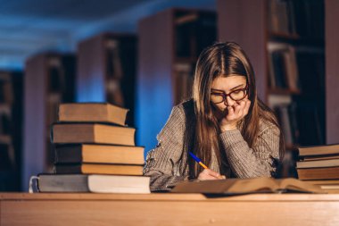 Gözlüklü genç öğrenci sınava hazırlanıyor. Akşamları kütüphanedeki masada bir yığın kitapla oturan bir kız..