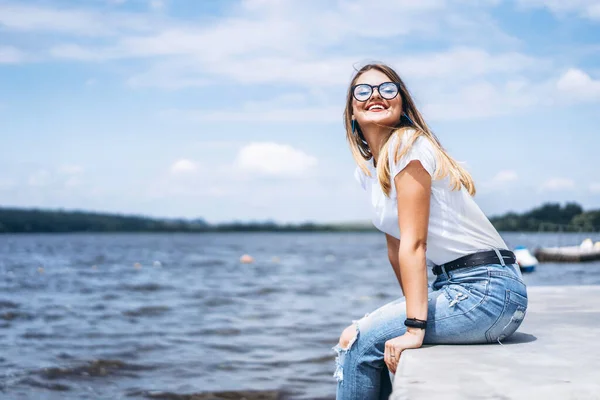 Mladá Žena Dlouhými Vlasy Stylových Brýlích Pózující Betonovém Břehu Jezera — Stock fotografie