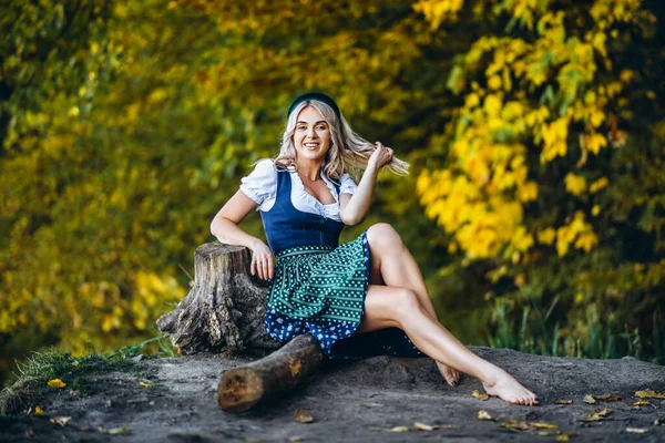 Oktoberfest 圣帕特里克日 故意啤酒日 赤脚快乐的金发姑娘 穿着传统的啤酒节礼服 坐在户外 身后是五彩斑斓的树木 — 图库照片