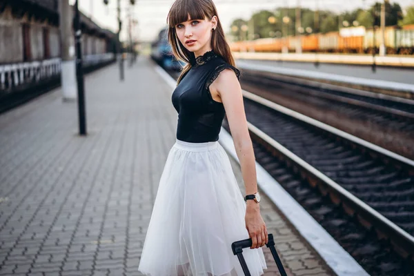 身穿白色短裙 头戴红色行李箱的黑发女旅行者等着火车 在地铁站上走着 — 图库照片