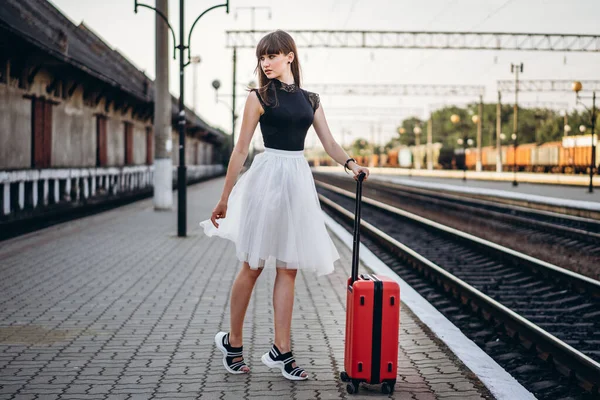 身穿白色短裙 头戴红色行李箱的黑发女旅行者等着火车 在地铁站上走着 — 图库照片