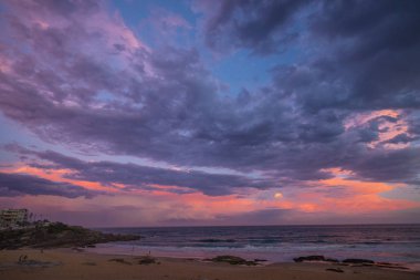 Sidney Avustralya 'da Maroubra sahilinde dramatik bir gün batımı. Kalın bulutlardan ve mor, mavi ve turuncu gibi canlı renklerden oluşur..