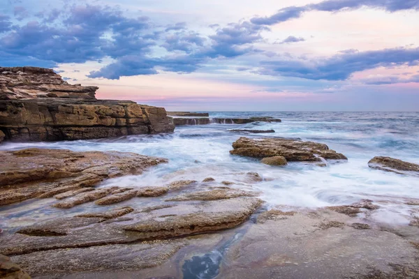 澳大利亚海岸线的长期曝光摄影 波浪从光滑的岩石上方流过 天空有一种宁静的色彩 — 图库照片