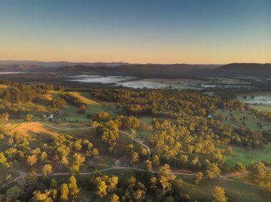 Yeni Güney Galler Avustralya 'daki Avcı Vadisi' nin gündoğumunda hava görüntüsü. Sis, dağlar, çalı, ağaçlar ve küçük çiftlik arazileri görebiliriz..