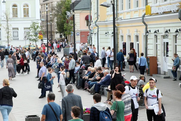 Bir sürü insan banklarda oturuyor ve sokakta yürüyor.