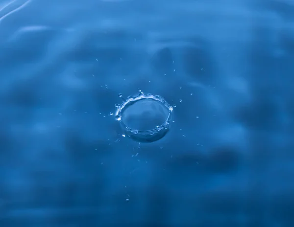 Water drop falling and drips on mirror. Water drop splash and make perfect circles on water surface.