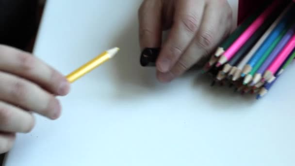 Muž zostřuje barevné tužky. — Stock video