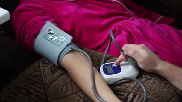 Monitoreo del estado físico en casa. El marido mide la presión arterial . — Vídeos de Stock