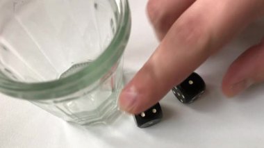 Zar atma. Adam bir cam içine küpleri toplar, onları sallıyor ve onları masaya atar.