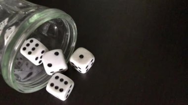 Zar atma. Adam bir cam içine küpleri toplar, onları sallıyor ve onları masaya atar.