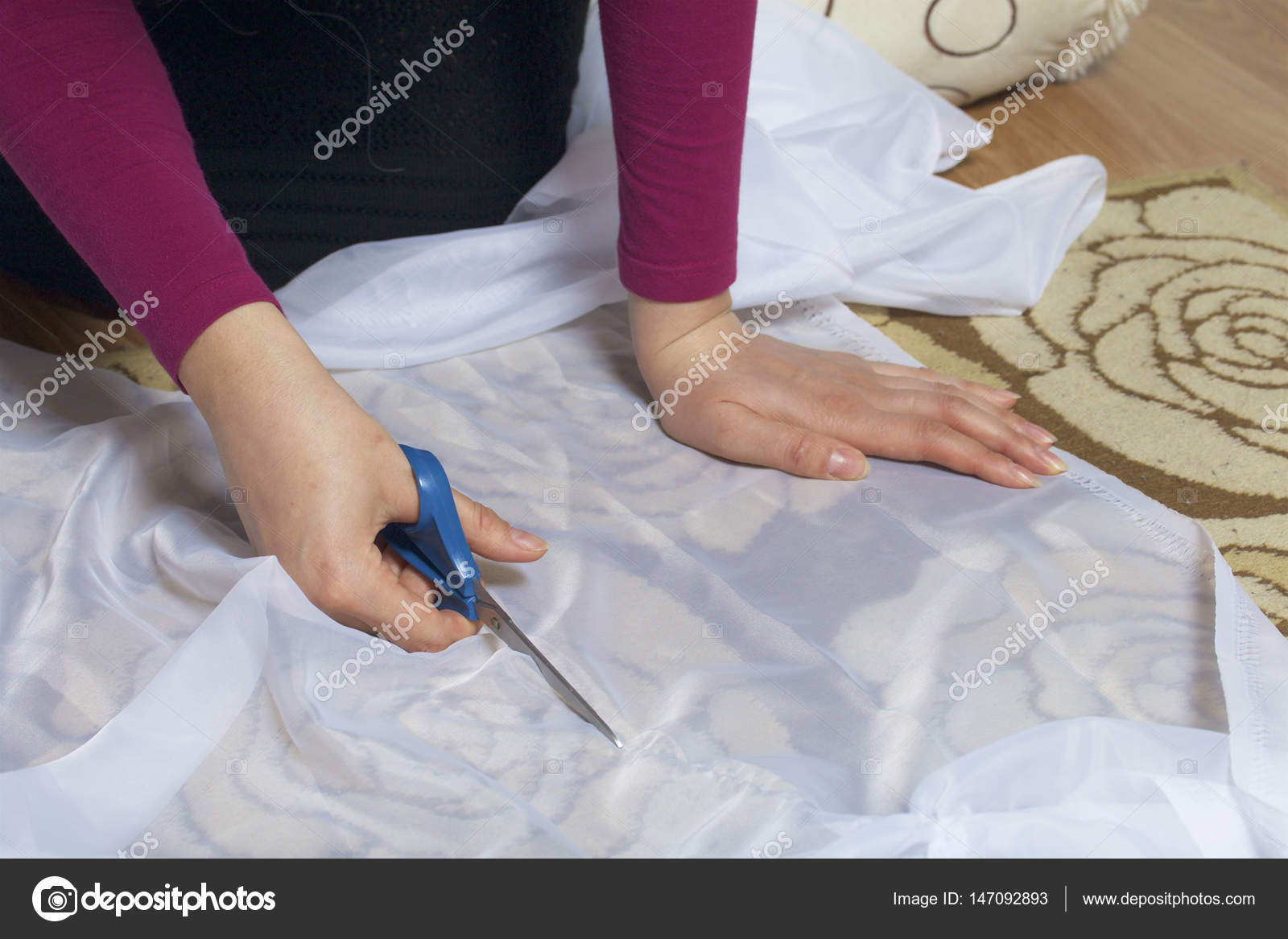 De vrouw snijdt het weefsel met een schaar voor naaien gordijnen op ... De vrouw snijdt het weefsel met een schaar voor naaien gordijnen op ...