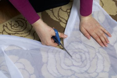 Kadın kumaş dikiş perdeler için makas ile cama keser.