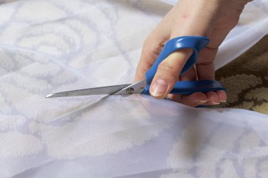 Kadın kumaş dikiş perdeler için makas ile cama keser.