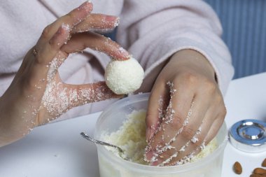 Raffaello tatlılar evde hazırlanması. Bir kadın bir top bir karışımı yoğunlaştırılmış süt ve Hindistan cevizi cips alır..