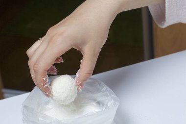 Raffaello tatlılar evde hazırlanması. Bir kadın bir top bir karışımı yoğunlaştırılmış süt ve Hindistan cevizi cips alır..