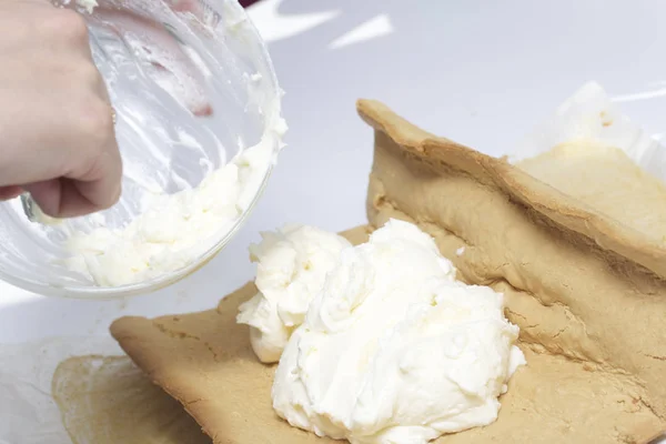 Preparation of biscuit rolls. Stages of preparation. The woman adds the filling to the biscuit.