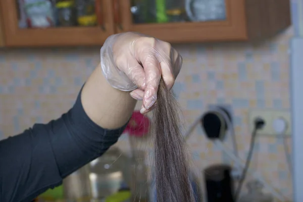 Индивидуальный предприниматель предоставляет услуги на дому. Парикмахер рисует волосы женщины. Расчесывание и распределение прядей . — стоковое фото