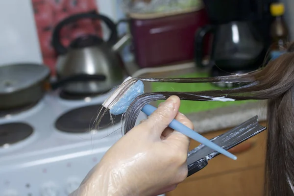 Enskild företagare tillhandahåller tjänster hemma. Frisören målar håret av en kvinna. Pensel färg på delarna. — Stockfoto