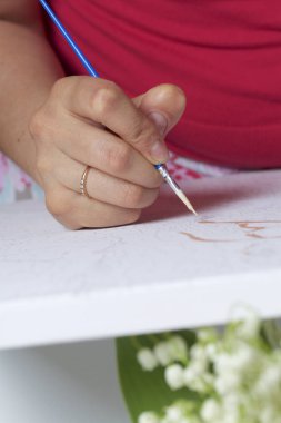 Sanat. Sayılarla çizim. Bir kadın bir tuval pamuk boyar. Fırçalar, boyalar ve su bir bardak sayılı kullanır.