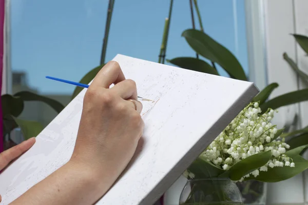 Art. Dibujo por números. Una mujer pinta un lienzo de algodón. Utiliza pinceles, pinturas numeradas y agua en un vaso . —  Fotos de Stock