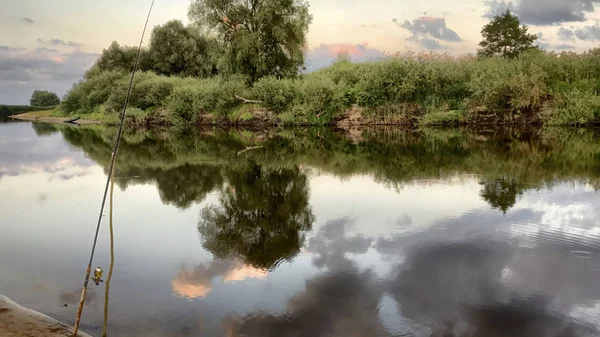 川の土手の夕暮れ。空には多くの雲があります。旅行や自然の中のレクリエーションです。パノラマ. — ストック写真
