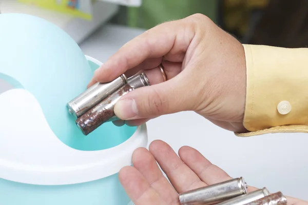 The man holds the batteries in his hand. With the other hand, he is ready to throw them into a special container. Utilization and processing of environmentally hazardous waste. — Stock Photo, Image