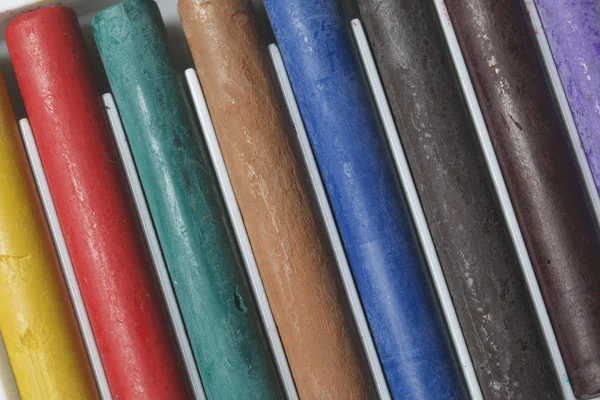 Farklı renklerde boya kalemi pastel. Bir kutu içinde onların yerleri, yalan. Beyaz bir arka plan üzerinde. Karede çapraz olarak.