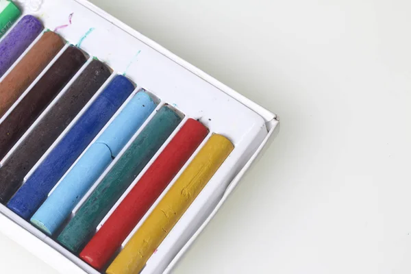 Crayons pastéis em cores diferentes. Deitado numa caixa nos seus lugares. Num fundo branco. Diagonalmente através da moldura . — Fotografia de Stock