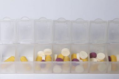 Tabletler ve hapları bir kaba tabletler için haftanın günlerini yayılmıştır. İlaçlar farklı şekiller ve renkler.