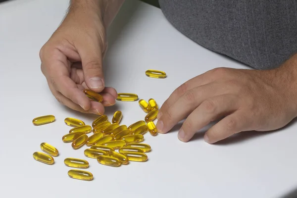 El hombre recoge pastillas de color amarillo de la mesa . —  Fotos de Stock