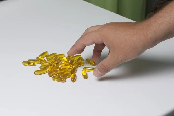 El hombre recoge pastillas de color amarillo de la mesa . —  Fotos de Stock
