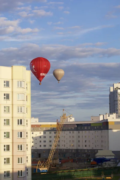 Parad av ballonger över staden. Aerostats i olika färger flyga i den blå himlen ovanför husen. — Stockfoto