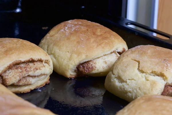 Preparazione di rotoli di cannella. La teglia tirata fuori dal forno. Ci sono panini pronti e un rotolo con sopra la cannella. . — Foto Stock