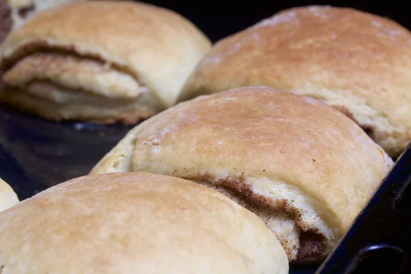 Preparazione di rotoli di cannella. La teglia tirata fuori dal forno. Ci sono panini pronti e un rotolo con sopra la cannella. . — Foto Stock