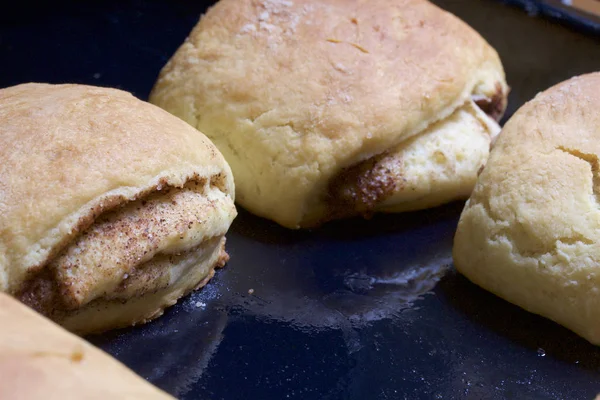 Preparazione di rotoli di cannella. La teglia tirata fuori dal forno. Ci sono panini pronti e un rotolo con sopra la cannella. . — Foto Stock