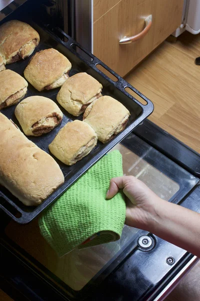 Rulo tarçın hazırlanması. Kadın bir fırın tepsisine fırından alır. Orada hazır çörekler ve tarçın ile bir atışında.