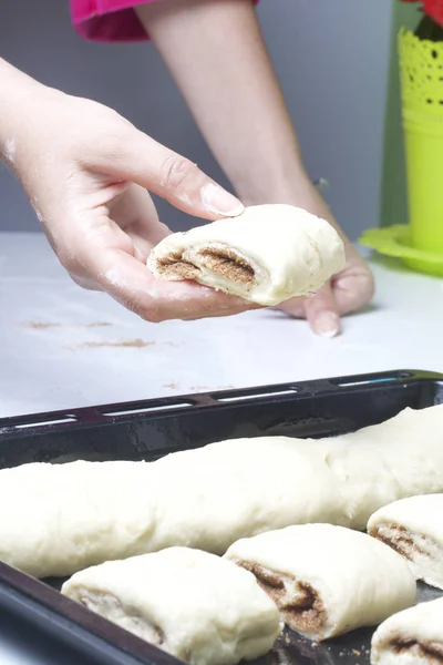 계피 롤의 준비. 빵굽는 쟁반 위에 빵 몇 개를 놓는 여자. — 스톡 사진