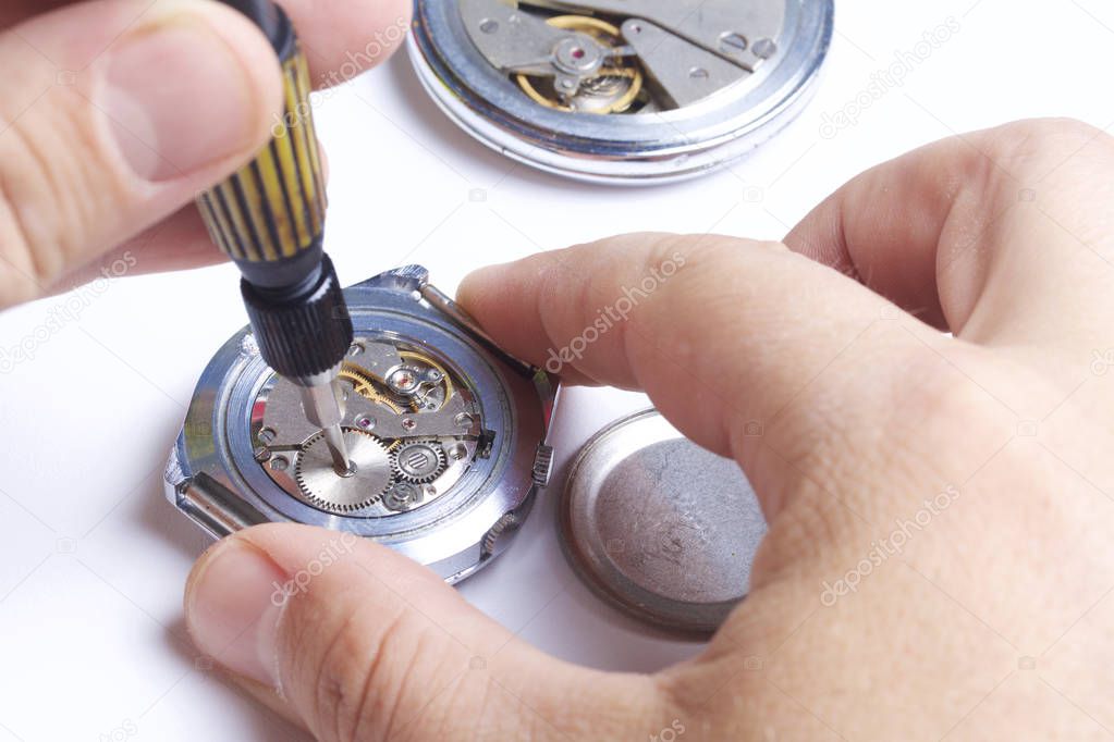 The watch workshop. Repair of old watches. The mechanism of the clock, the screwdriver, which the master makes repairs, is visible. On a white background.