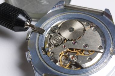 The watch workshop. Repair of old watches. The mechanism of the clock, the screwdriver, which the master makes repairs, is visible. On a white background. clipart