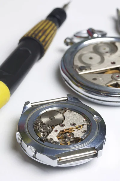 Watch atölye. Eski saatleri tamir. Saat, ana yapar onarır, tornavida, görünür bir mekanizmadır. Beyaz bir arka plan üzerinde.