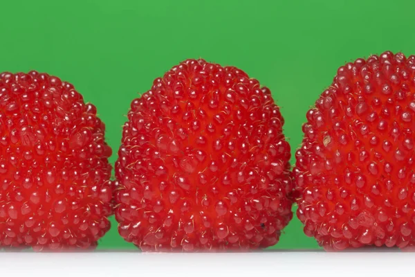 Las bayas rojas grandes son similares a las frambuesas. Sobre un fondo verde . —  Fotos de Stock