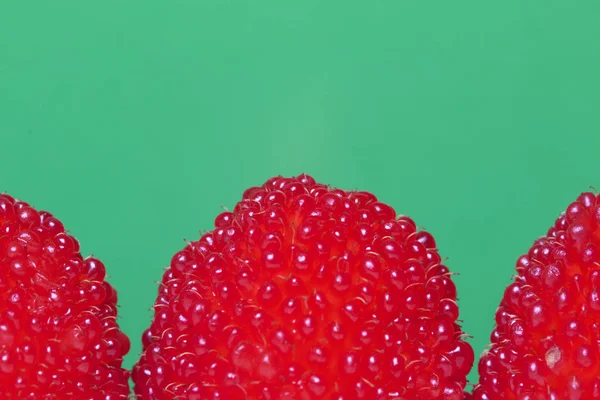 Velké červené bobule jsou podobné maliny. Na zeleném pozadí. — Stock fotografie