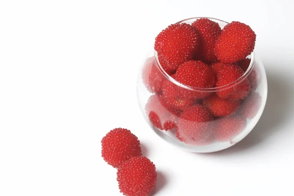 Große rote Beeren ähneln Himbeeren in einer Glasvase. auf weißem Hintergrund. Blick von oben. — Stockfoto