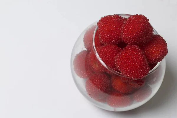 Большие красные ягоды похожи на малину в стеклянной вазе. На белом фоне. Вид сверху . — стоковое фото