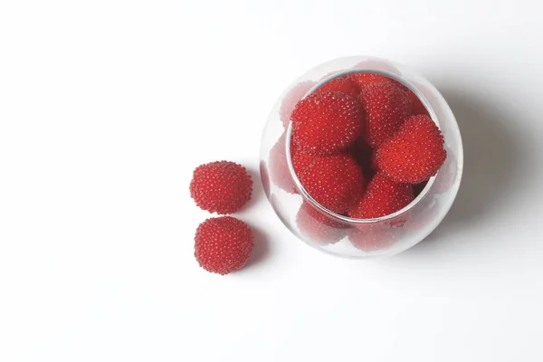 As grandes bagas vermelhas são semelhantes a framboesas em um vaso de vidro. Num fundo branco. Vista de cima . — Fotografia de Stock