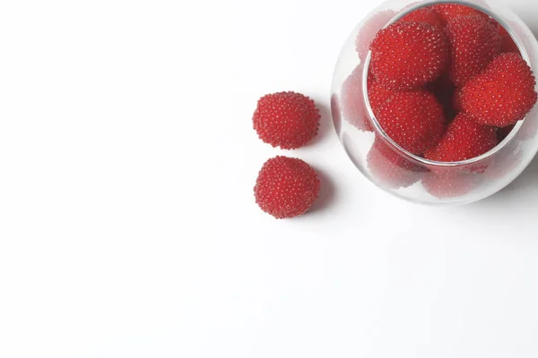 Velké červené bobule jsou podobné maliny ve skleněné váze. Na bílém pozadí. Pohled shora. — Stock fotografie