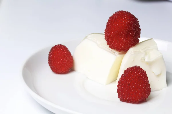 Jalea de crema agria, decorada con frambuesas. Se acuesta en un plato. Sobre un fondo blanco . — Foto de Stock